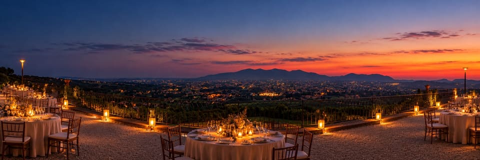 Tavoli apparecchiati a lume di candela sulla terrazza della Specola al tramonto, con la piana di Lucca illuminata e i monti all’orizzonte